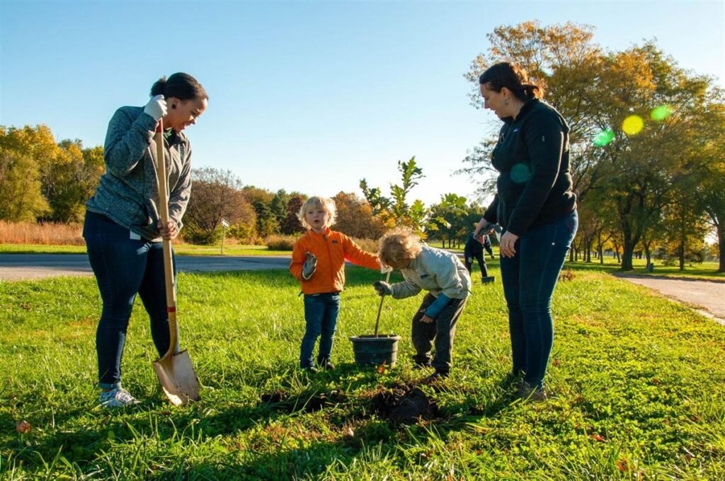 Family planting young trees in a public park to support environmental conservation in the USA.