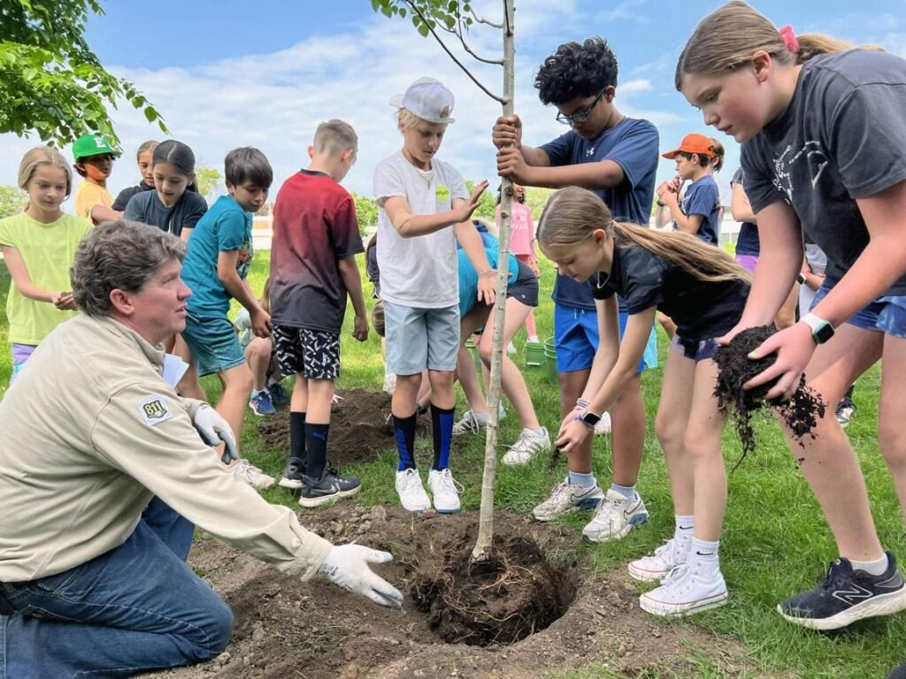 Students planting trees with their teacher as part of an environmental conservation program.